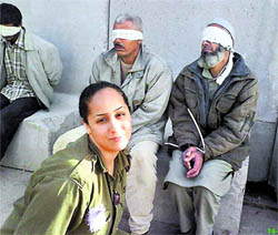 In this undated photo, originally posted on a Facebook page belonging to Eden Aberjil and taken from the Israeli blog site sachim.tumblr.com, an Israeli army soldier poses in front of blindfolded men identified in the Israeli new media as Palestinian prisoners