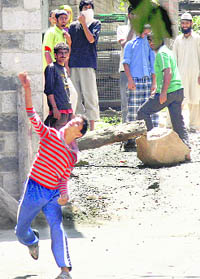  A youth throws stones  at security forces during a protest in Srinagar on Thursday.