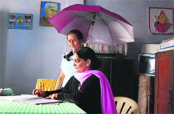 Headmistress Nimesh Dangwal of Government Girls Junior High School at Kuri works under the protection of an umbrella in a classroom.