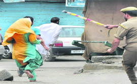 A woman is chased away by a policeman during a demonstration in Srinagar.
