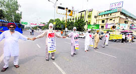 Riot victims form a chain at Bharat Nagar Chowk in Ludhiana on Friday