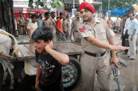 a policeman charges at a protester to send him away at the Grain Market in Bathinda.