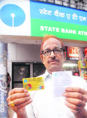 Hans Raj shows his card in front of the ATM of the SBI at Sector 17 in Chandigarh on Saturday.