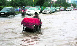 A vendor pushes his rehri on a flooded road after a heavy rain in Gurgaon on Saturday