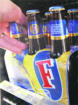 A customer takes a six-pack of Foster's beer at a liquor store in Melbourne on Monday.