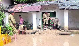 Firefighters drain out rainwater from a house near Palampur on Monday.