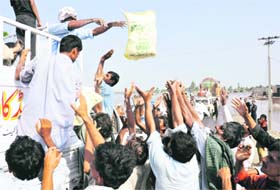 Flood victims receive food distributed by a local charity in Mehmood Kod village in Muzaffargarh district of Punjab province