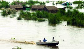 Delhi government relief officials ride past submerged huts in the overflowing Yamuna river in New Delhi on Tuesday.