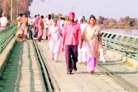 People walk across the Gidder Pindi bridge over the Sutlej after rail and vehicular traffic was stopped on it