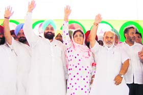 (From right) Rajinder Kaur Bhattal and Partap Singh Bajwa raise their hands at a rally at Baba Bakala