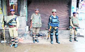 CRPF jawans stand guard in front of closed shops in curfew-bound Srinagar