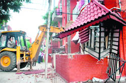 A JCB machine demolishes a part of a building in Chandigarh on Friday.