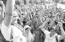 Workers of the Aanganwari Workers and Helpers Union block a road in Panchkula on Thursday. 
