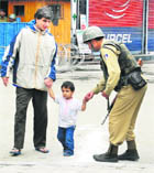 A CRPF jawan plays with a child on a deserted street in Srinagar on Thursday. 