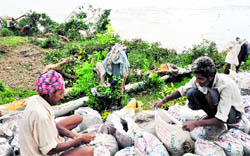 Workers fill sand bags to repair the trench in the dhussi 