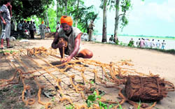 A man prepares jute cords to make stud and spur barriers for the dhussi bundh at Madepura village.