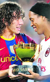 Barcelona's captain Carles Puyol (L) gives the Joan Gamper trophy to AC Milan's player Ronaldinho after Barcelona won the trophy in their friendly match at Camp Nou stadium in Barcelona on Wednesday.