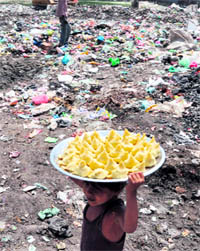 A child carry samosas in a pan near open garbage dump at Sherpur in Ludhiana