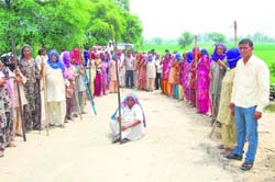 Women armed with lathis and farm implements assemble to protest in fields of Gorakhpur village, where the NPCIL wants to set up a power plant in Fatehabad. 