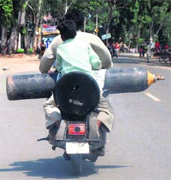 Unmindful of the risks involved, these scooter-borne persons carry a commercial gas cylinder in Karnal. 