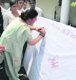 Geeta Bhukkal, state Health Minister, pays tributes to martyrs by writing a message on a banner at an exhibition in Jhajjar.