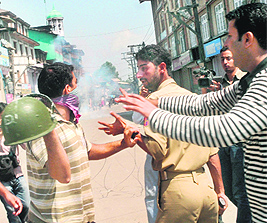 A protester tries to hit a policeman during a clash in the Maisuma area in Srinagar on Monday.