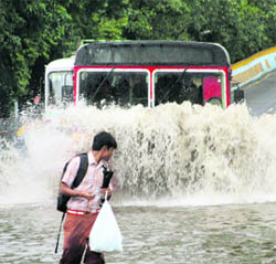 A schoolboy wades through a flooded Mumbai street after heavy showers lashed the city on Tuesday.