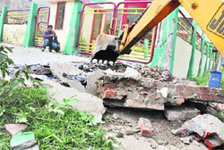 An illegal ramp being razed outside a house at BRS Nagar on Wednesday.
