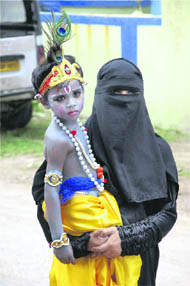  A Muslim woman carries her son, dressed as Lord Krishna, for a school function to celebrate Janmashtami, in Patna on Wednesday.