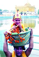 A man carries a boy dressed as Lord Krishna on his head at the Durgiana Temple on the occasion of Janmashtami 