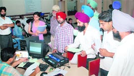An official at the Suvidha Centre manually processes documents after the computer system was damaged due to high voltage at the Mohali District Administrative Complex on Friday.