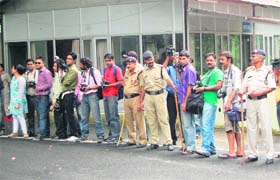 Media persons (in a long queue) wait outside the state Secretariat for an opportunity to click MS Dhoni in Dehradun