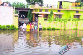 People stand in knee-deep water outside their house following heavy rains in Dehradun