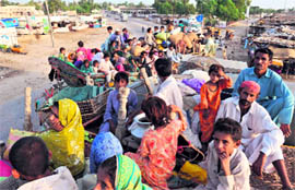 Survivors sit on a trucks as they evacuate the flooded area of Sehwan 