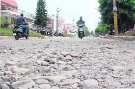 Motorists have a tough time riding through a damaged road in Sector 7 of Karnal.