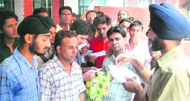A security guard at the Punjab School Education Board office, Mohali, distributes slips for duplicate roll numbers among students on Monday.