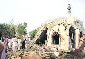 People gather at the site of a suicide bombing at a police station in Lakki Marwat, Pakistan, on Monday. A suicide bomber detonated a car in an alley behind a police station here killing 19 persons, including policemen and civilians, in an explosion that shattered the station and neighboring homes. 