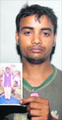 Karfew with the picture of his father Prajapati, who died in an accident.
