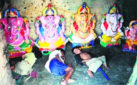 Children of vendors take a nap near idols of Lord Ganesha in Jammu.