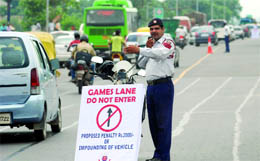 A Delhi traffic policeman signals commuters to steer away from the dedicated lane for the Commonwealth Games during a trial run in New Delhi on Wednesday