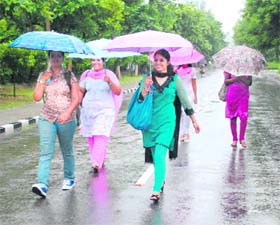 Girls protect themselves from the rain on the Punjabi University campus in Patiala