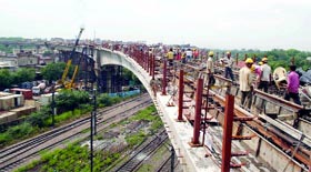 Workers lay tracks on a 100-metre-long Metro bridge being constructed over railway tracks at Okhla in New Delhi on Thursday.