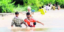 Villagers cross a bridge under flood waters at Nangli village in Karnal.