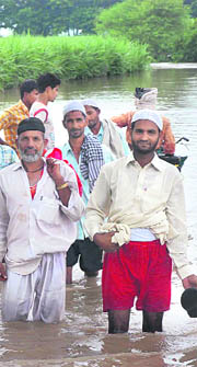 A group of devout Muslims from Sayyad Chapra wade through the Yamuna at Nangli village to offer Friday prayers, a day before Eid.