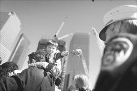 A two-year-old boy sits on his fathers shoulder as he offers rose to a fire fighter who was guarding the reflecting pool in New York on Saturday. The childs uncle was a victim of the 9/11 attacks on the World Trade Center.
