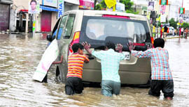 Children push a vehicle on a water-logged road in Haridwar on Sunday