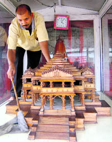 A worker cleans a wooden replica of the proposed Ram Temple at a workshop in Ayodhya