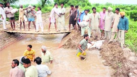 Farmers try to plug the breach in a distributary near Kot Bhara village in Bathinda district on Sunday.