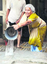 A woman throws rainwater out of her home in Haridwar.