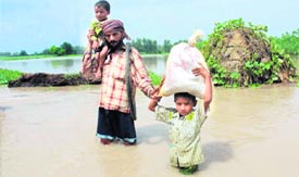 A villager with his children on a flooded road at Nangli village in Karnal.